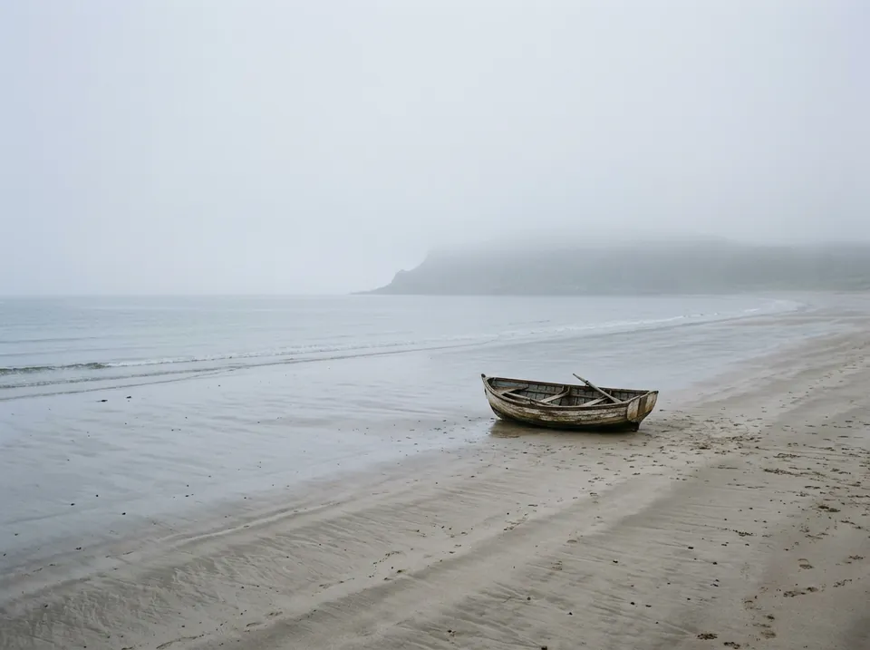 Playa con niebla y una barca en la arena